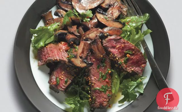Gebratenes asiatisches Steak und Pilze auf gemischtem Gemüse mit Ingwerdressing