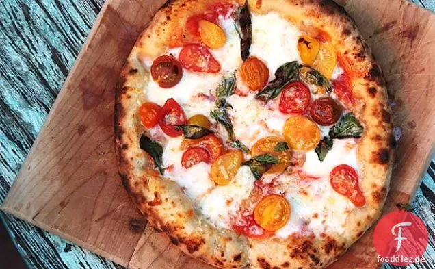 Pizza mit Kirschtomaten, Knoblauch, Basilikum und Mozzarella