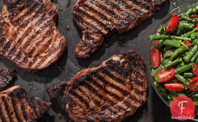 Gewürzgeriebene gegrillte Rippensteaks mit grüner Bohne und Kirschtomatensalat