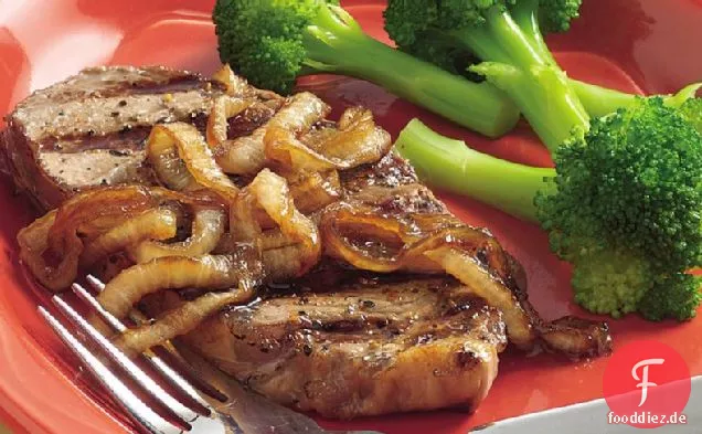 Pfeffer-geriebene gegrillte Steaks mit karamellisierten Zwiebeln