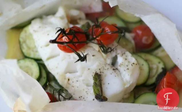 Frischer Kabeljau in einer Papiertüte mit Zucchini, Tomaten und Minze