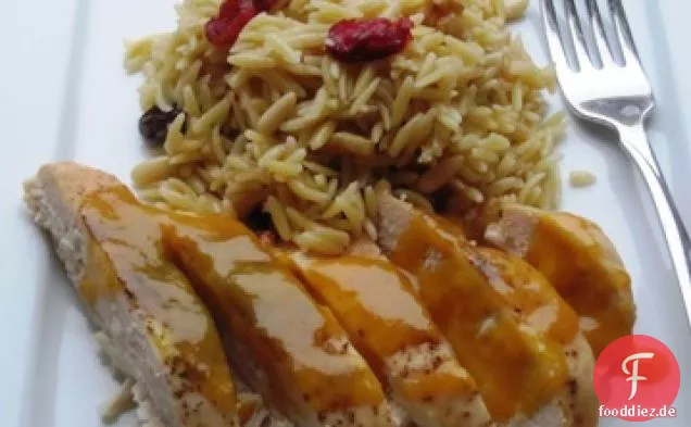Huhn mit Passionsfruchtsauce über getrockneten Früchten und Nüssen Orzo