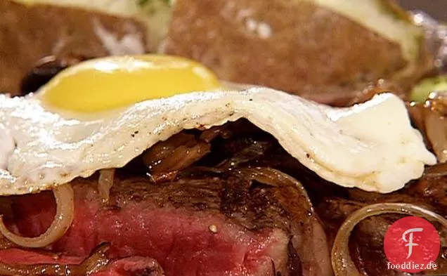 Bier Mariniertes T-Bone-Steak, sautierte Zwiebeln und Pilze, garniert mit einem Spiegelei