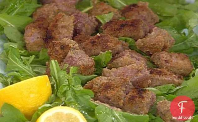 Rinderfilet beißt auf einem Bett aus Rucola