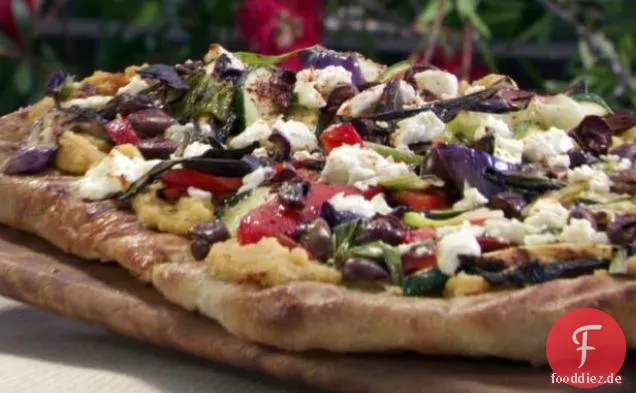 Gegrillte Pizza mit würzigem Hummus, Gemüse, Ziegenkäse und schwarzen Oliven
