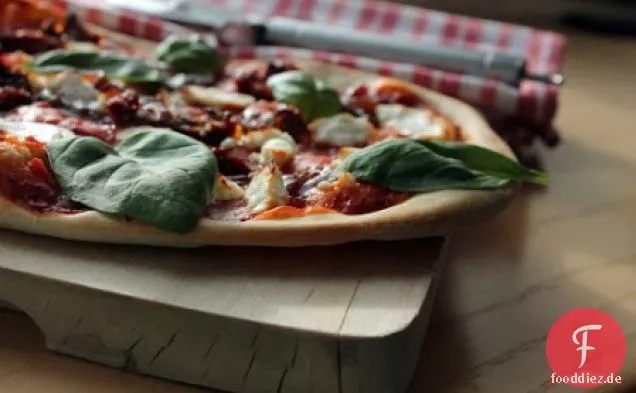 Pizza mit Ziegenkäse, getrockneten Tomaten und karamellisierten Zwiebeln