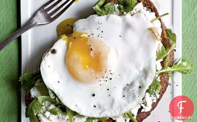 Sandwiches mit offenem Gesicht mit Ricotta, Rucola und Spiegelei